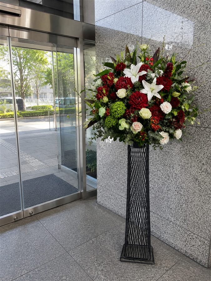 お届け先ビルのエントランス脇に設置したスタンド花のお届け完了報告写真(イメージ)